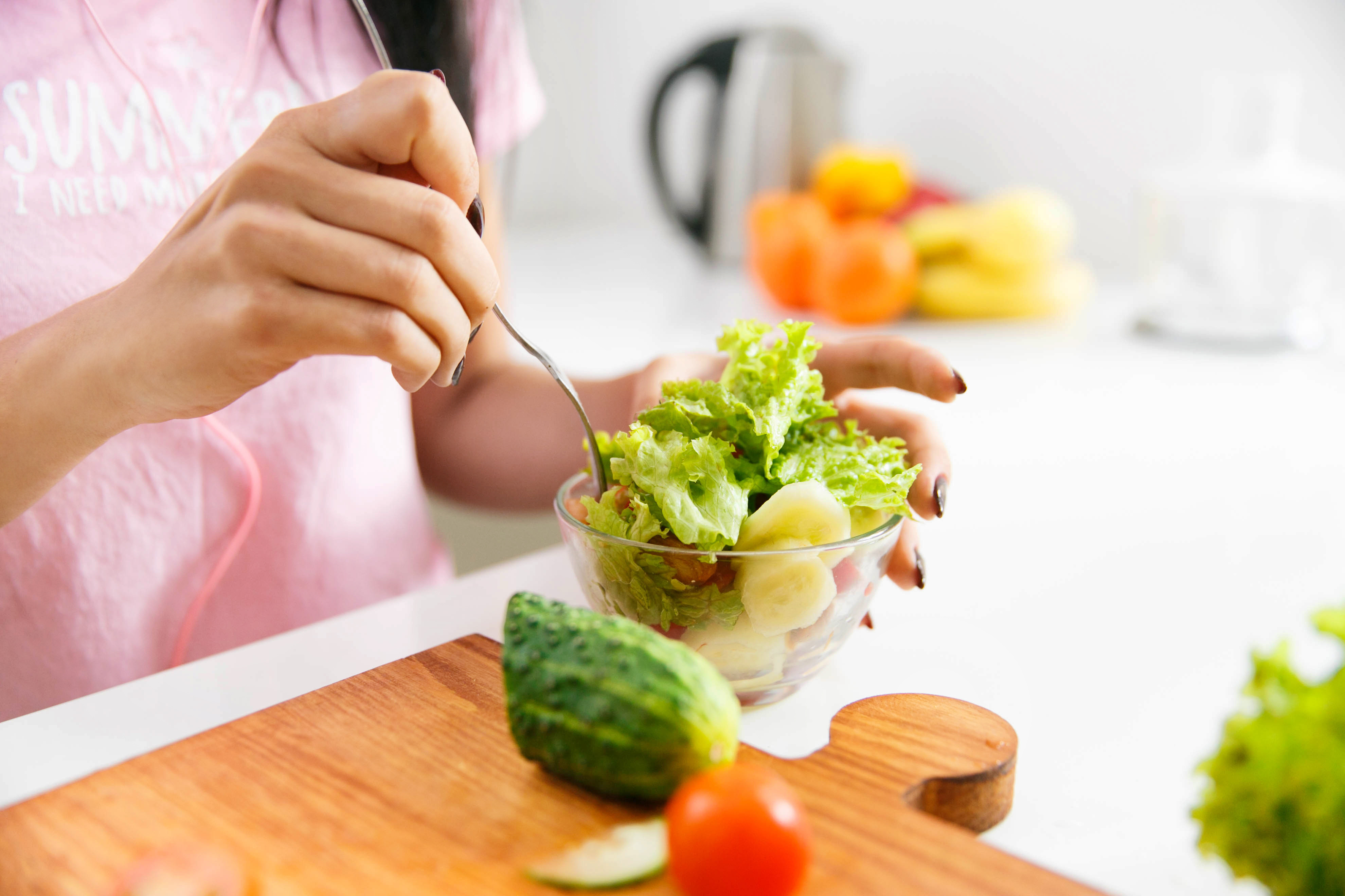 Close-up of woman's hands mixing salad in the kitchen